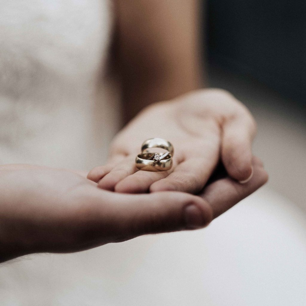 Couple holding wedding rings.